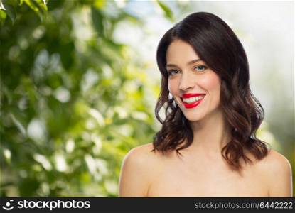 beauty, make up and people concept - happy smiling young woman with red lipstick over green natural background. beautiful smiling young woman with red lipstick