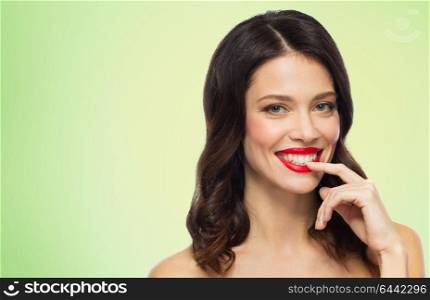beauty, make up and people concept - happy smiling young woman with red lipstick posing over green background. beautiful smiling young woman with red lipstick
