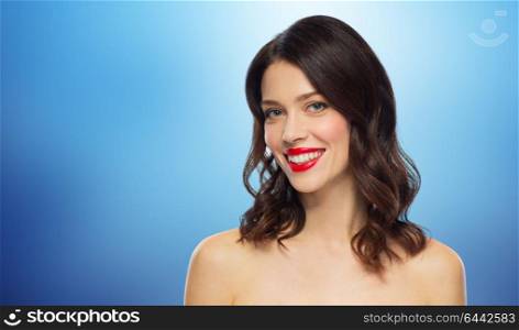 beauty, make up and people concept - happy smiling young woman with red lipstick over blue background. beautiful smiling young woman with red lipstick