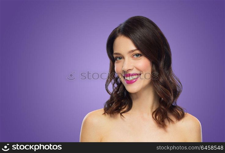 beauty, make up and people concept - happy smiling young woman with berry lipstick posing over ultra violet background. beautiful woman with lipstick over ultra violet
