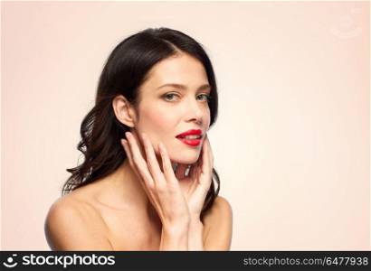beauty, make up and people concept - happy smiling young woman with red lipstick over beige background touching her face. beautiful smiling young woman with red lipstick. beautiful smiling young woman with red lipstick