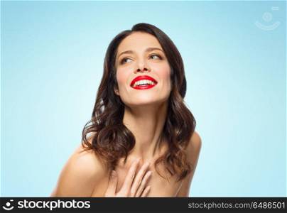 beauty, make up and people concept - happy smiling young woman with red lipstick posing over blue background. beautiful smiling young woman with red lipstick. beautiful smiling young woman with red lipstick