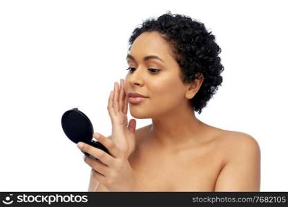 beauty, make up and people concept - portrait of young african american woman with bare shoulders looking to mirror and touching her face over white background. african american woman looking to mirror