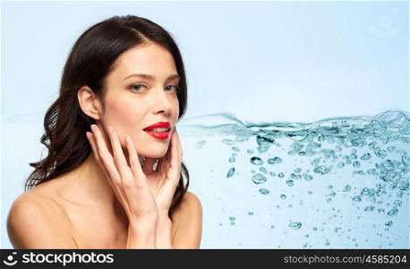 beauty, make up and skin moisturizing concept - happy smiling young woman with red lipstick touching her face over blue background and bubbles in water . beautiful smiling young woman with red lipstick. beautiful smiling young woman with red lipstick