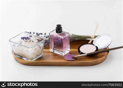 beauty, make up and wellness concept - sea salt, perfume, lavender and mineral cosmetics on wooden tray. sea salt, perfume and lavender on wooden tray
