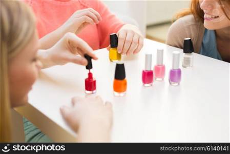 beauty, make up, cosmetics and people concept - close up of smiling young women or teenage girls with nail polish on table