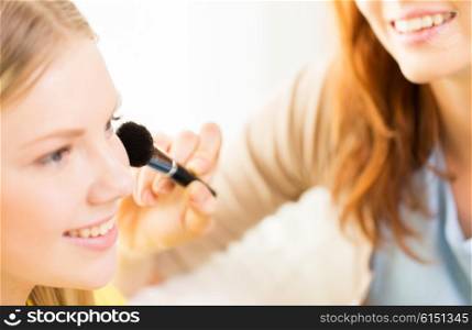 beauty, make up, cosmetics and people concept - close up of smiling young woman and visagist or friend with blush and makeup brush