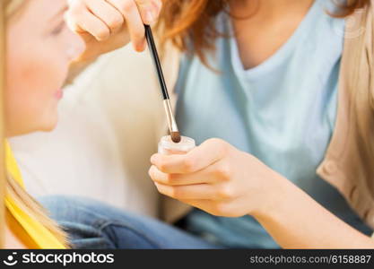 beauty, make up, cosmetics and people concept - close up of smiling young woman and visagist or friend with makeup brush and eyeshadow
