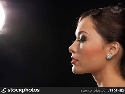 beauty, make-up, jewellery and nightlife concept - profile portrait of beautiful woman wearing diamond earrings