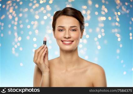 beauty, makeup and cosmetics concept - happy smiling young woman with pink lipstick over holidays lights on blue background. beautiful smiling young woman with pink lipstick
