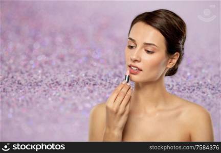 beauty, makeup and cosmetics concept - happy smiling young woman with pink lipstick over shimmering violet glitter on background. beautiful smiling young woman with pink lipstick
