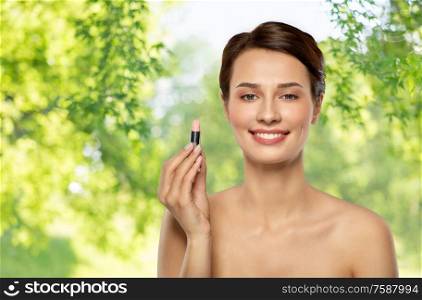 beauty, makeup and cosmetics concept - happy smiling young woman with pink lipstick over green natural background. beautiful smiling young woman with pink lipstick