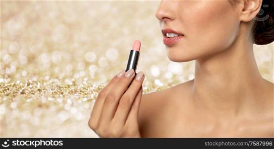 beauty, makeup and cosmetics concept - happy smiling young woman with pink lipstick over shimmering golden glitter on background. beautiful smiling young woman with pink lipstick
