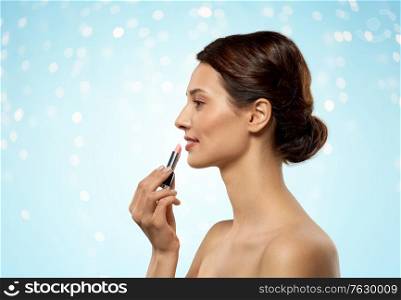beauty, makeup and cosmetics concept - happy smiling young woman with pink lipstick over lights on blue background. beautiful smiling young woman with pink lipstick