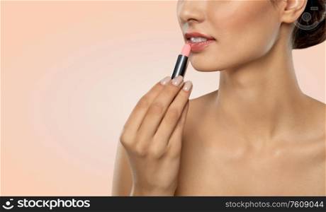 beauty, makeup and cosmetics concept - happy smiling young woman with pink lipstick over beige background. beautiful smiling young woman with pink lipstick