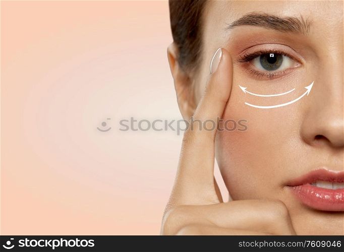 beauty, makeup and lifting concept - close up of beautiful young woman face with arrows under eye area over beige background. close up of young woman face with arrows under eye