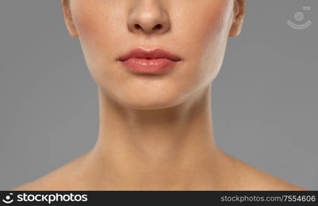 beauty, makeup and people concept - close up of beautiful young woman face and neck over grey background. close up of beautiful young woman face and neck