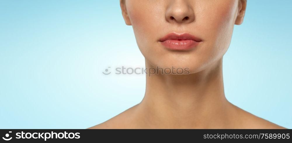 beauty, makeup and people concept - close up of beautiful young woman face and neck over blue background. close up of beautiful young woman face and neck