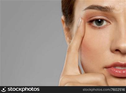 beauty, makeup and vision concept - close up of beautiful young woman face and eyes over grey background. close up of beautiful young woman face and eyes