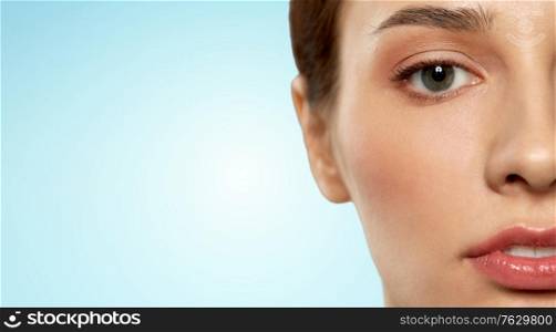 beauty, makeup and vision concept - close up of beautiful young woman face and eyes over blue background. close up of beautiful young woman face and eyes