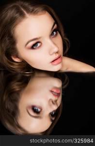 Beauty makeup fashion model on mirror with pink lips reflection black background