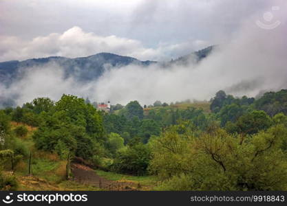 beauty mountain landscape with alone building and mist over the mountain