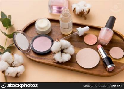 beauty, natural cosmetics and make up products concept - makeup, perfume with cotton flower on wooden tray and eucalyptus cinerea. makeup, perfume and cosmetics on wooden tray