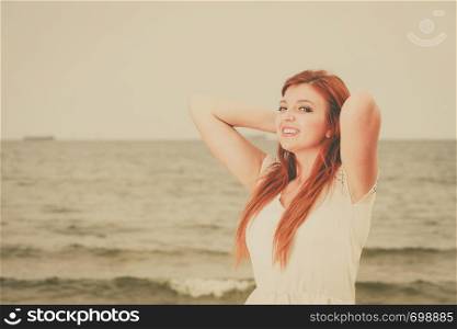 Beauty of ginger hair concept. Portrait of beautiful happy redhead adult woman during summertime, sea water in background.. Portrait of beautiful redhead adult woman