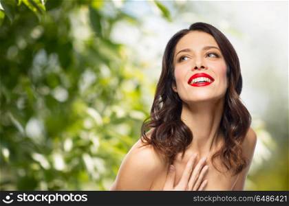 beauty, organic and eco concept - happy smiling young woman with red lipstick posing over green natural background. beautiful smiling young woman with red lipstick. beautiful smiling young woman with red lipstick