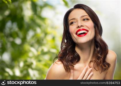beauty, organic, make up and people concept - happy laughing young woman with red lipstick over green natural background. beautiful laughing young woman with red lipstick