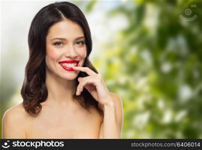 beauty, organic, make up and people concept - happy smiling young woman with red lipstick posing over green natural background. beautiful smiling young woman with red lipstick