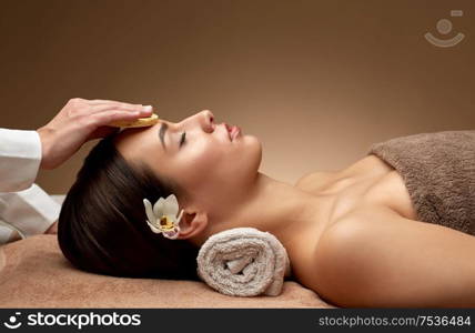 beauty, pampering and relaxation concept - close up of beautiful young woman lying with closed eyes and having face massage with sponge in spa. close up of woman having face massage in spa