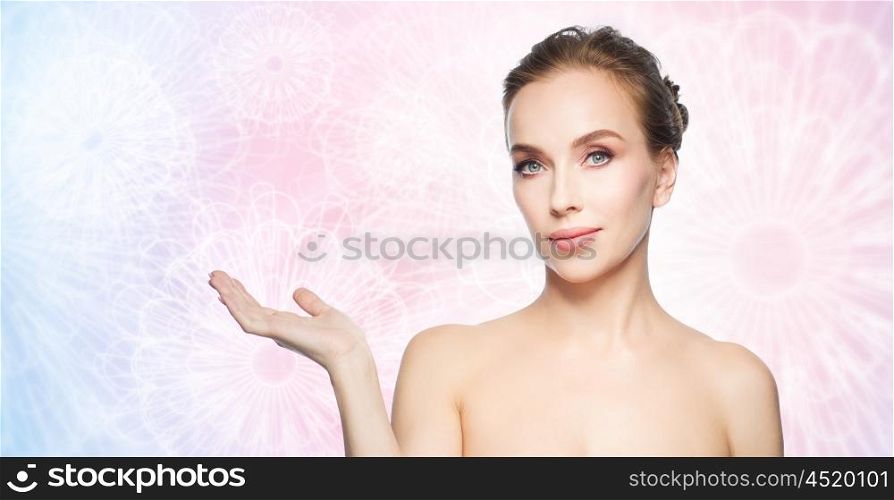 beauty, people, advertisement and health concept - smiling young woman holding something on palm of her hand over rose quartz and serenity patterned background