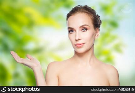beauty, people, advertisement, eco and health concept - smiling young woman holding something on palm of her hand over green natural background