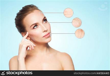 beauty, people, aging and skin care concept - beautiful young woman and circles with magnified facial wrinkles over blue background
