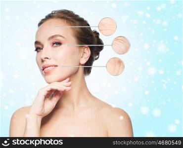 beauty, people, aging, winter and skin concept - beautiful young woman touching her face over blue background and snow