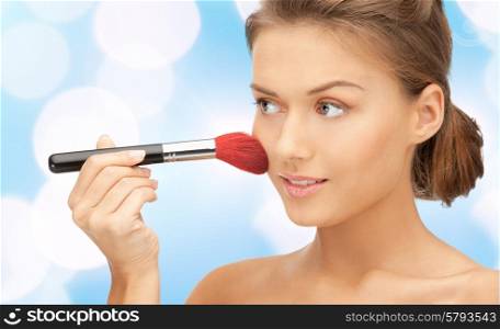 beauty, people and accessories concept - beautiful smiling woman with bare shoulders and make up brush over blue lights background