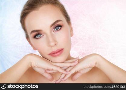 beauty, people and body care concept -beautiful young woman face and hands over rose quartz and serenity patterned background