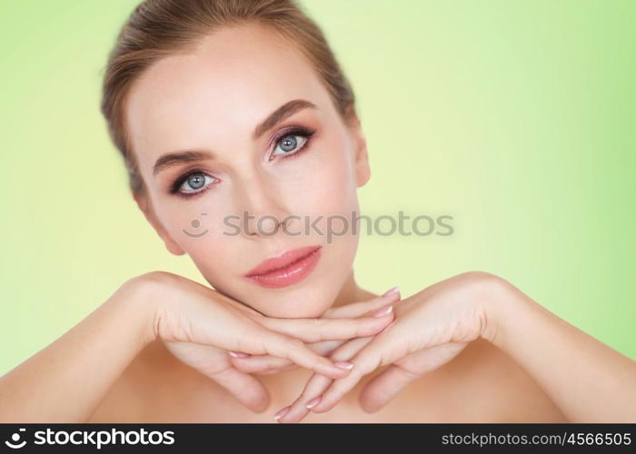 beauty, people and body care concept -beautiful young woman face and hands over green background