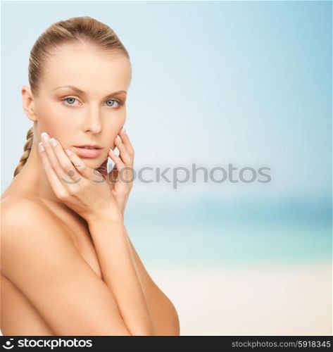 beauty, people and body care concept - beautiful young woman touching her face over blue background