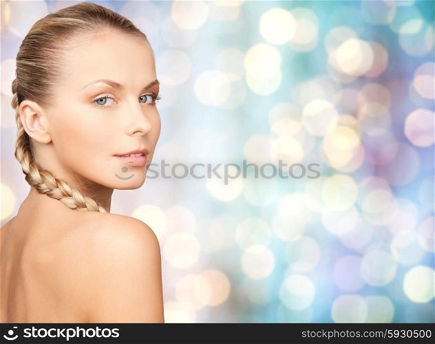 beauty, people and body care concept - beautiful young woman with bare shoulders over blue holidays lights background