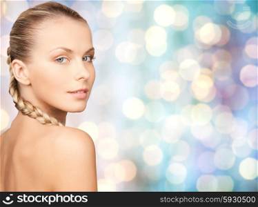 beauty, people and body care concept - beautiful young woman with bare shoulders over blue holidays lights background