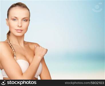 beauty, people and body care concept - beautiful young woman with bare shoulders over blue background
