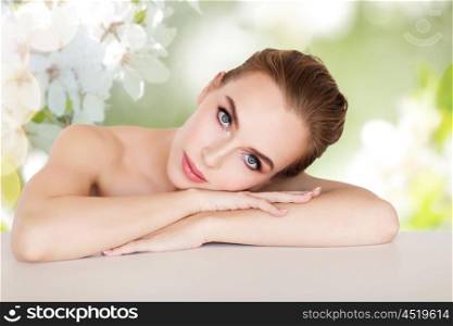 beauty, people and bodycare concept -beautiful young woman face and hands over natural spring cherry blossom background