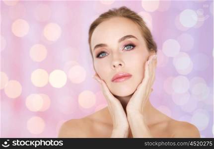 beauty, people and bodycare concept -beautiful young woman face and hands over rose quartz and serenity lights background