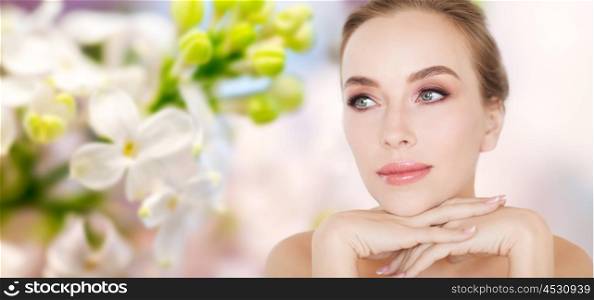 beauty, people and bodycare concept -beautiful young woman face and hands over natural lilac blossom background