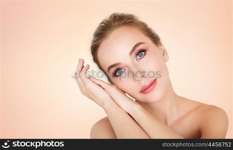 beauty, people and bodycare concept -beautiful young woman face and hands over beige background