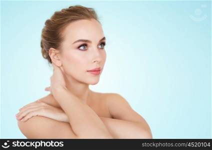 beauty, people and bodycare concept -beautiful young woman face and hands over blue background