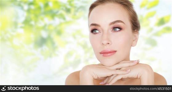 beauty, people and bodycare concept -beautiful young woman face and hands over green natural background