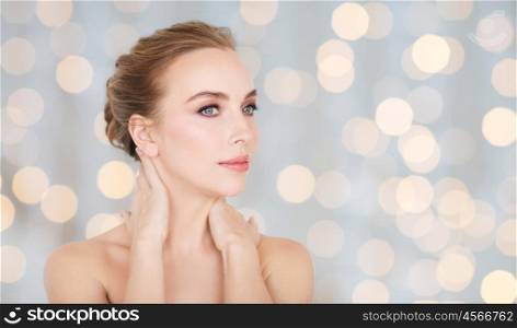 beauty, people and bodycare concept -beautiful young woman face and hands over holidays lights background